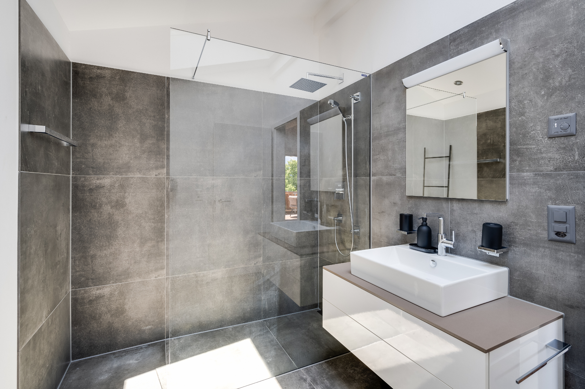 Modernes sauberes Badezimmer einer AlpineLake-Ferienwohnung mit Dusche, Glaswand, Waschbecken und Spiegel